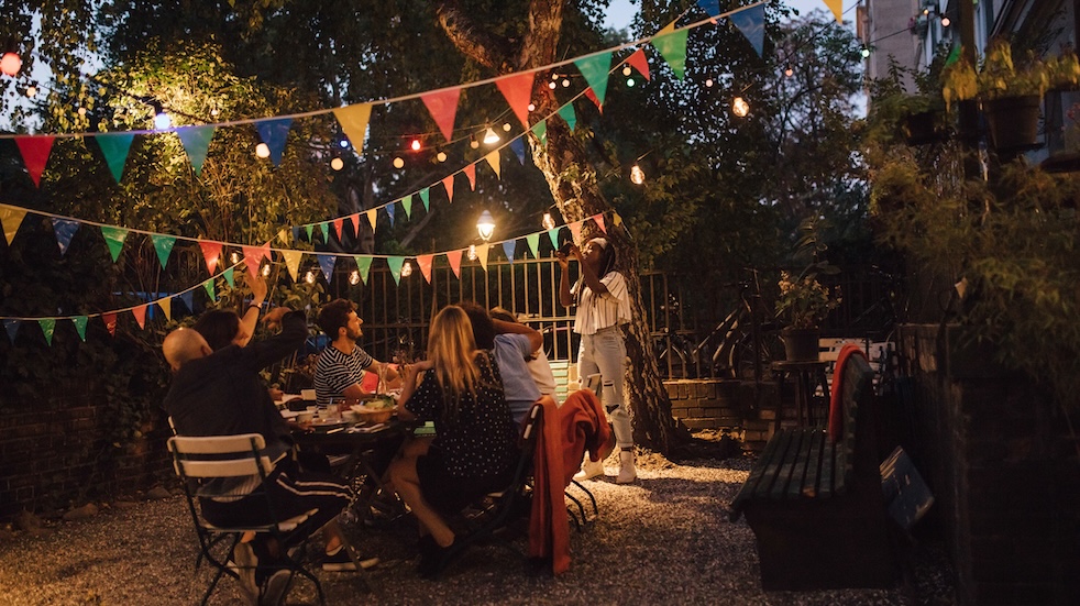 Young woman photographing friends during dinner party in backyard